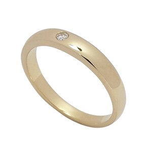 Könnte beinhalten: Ein einfacher Goldring mit einem kleinen Diamanten in der Mitte.