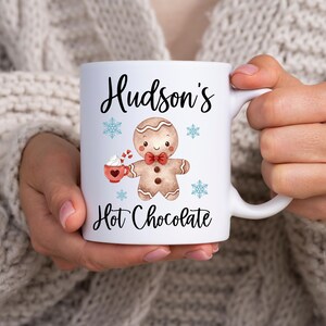 Puede incluir: Taza de cer&aacute;mica blanca con un dise&ntilde;o de hombre de jengibre y el texto "Hudson's Hot Chocolate".