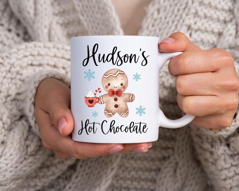 Puede incluir: Taza de cer&aacute;mica blanca con un dise&ntilde;o de hombre de jengibre y el texto "Hudson's Hot Chocolate".