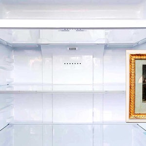 May include: An empty white refrigerator with a gold framed picture of a woman in a dress holding a child on the right side of the door.
