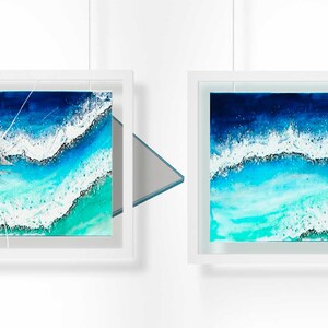 May include: Two framed paintings of ocean waves. The painting on the left has a cracked glass pane. The painting on the right has an intact glass pane.