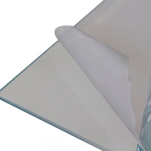 May include: A clear sheet of acrylic with a protective film on one side. The film is being peeled back to reveal the clear acrylic.