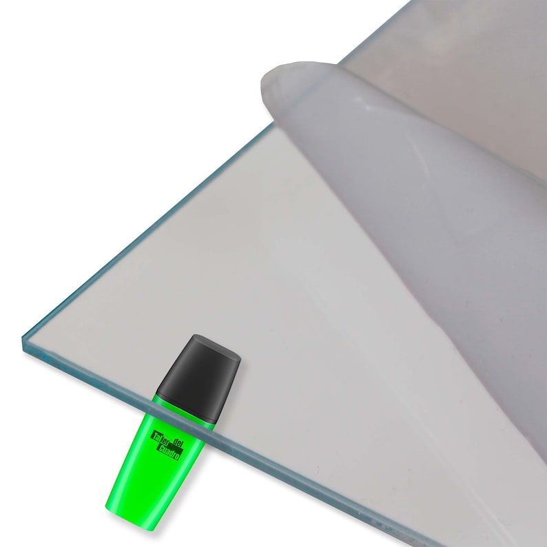 May include: A clear sheet of acrylic plastic with a protective film on one side. The sheet is resting on a white surface. A green highlighter is lying on the sheet.