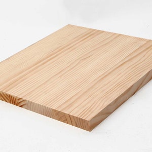 Può includere: Un pezzo rettangolare di legno grezzo di colore marrone chiaro. Il legno ha una superficie liscia ed è privo di nodi.