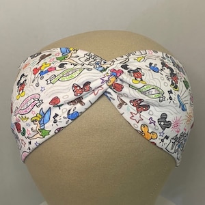 May include: White headband featuring a colourful print of various Disney characters, including Mickey Mouse, Minnie Mouse, Tinkerbell, and other iconic symbols. The headband is twisted and has a white background.
