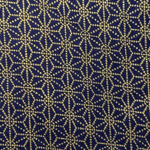 May include: A navy blue fabric with a gold geometric pattern. The pattern is made up of small circles and lines that create a repeating design.