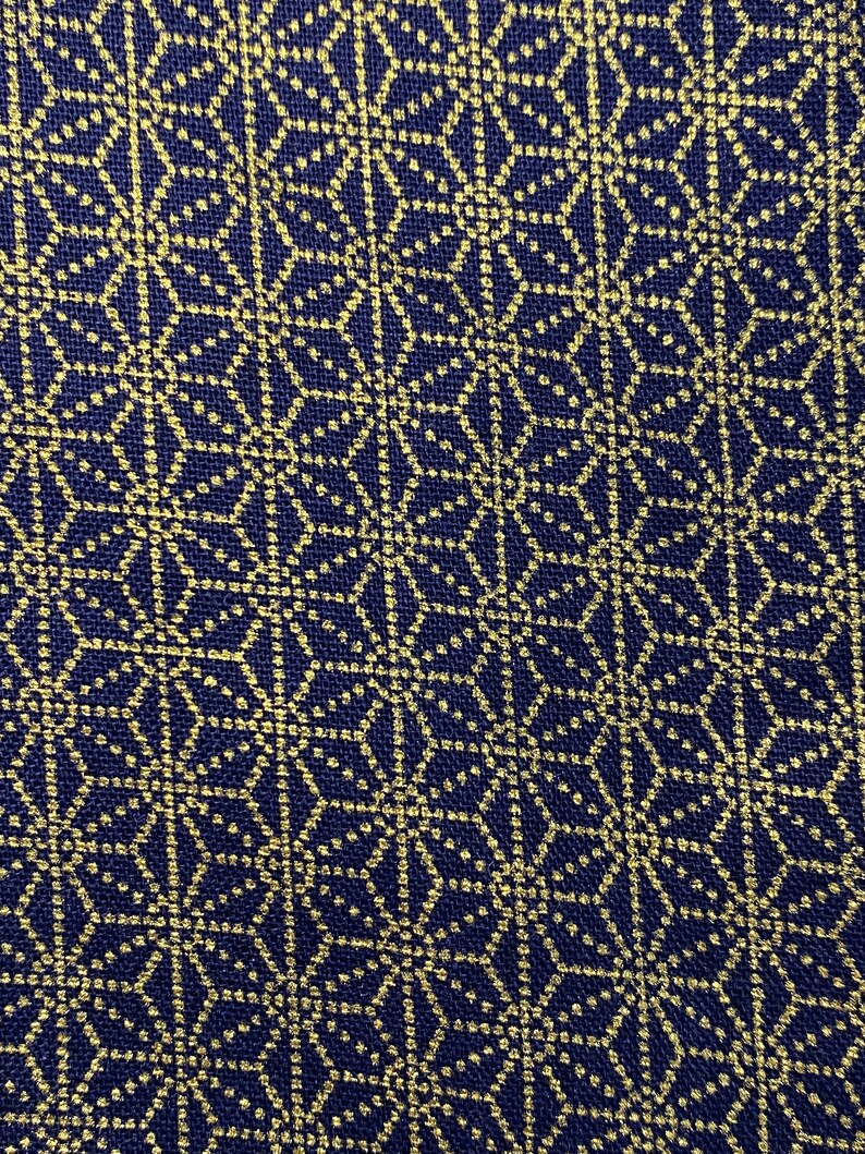 May include: A navy blue fabric with a gold geometric pattern. The pattern is made up of small circles and lines that create a repeating design.