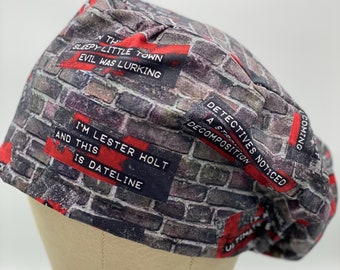 May include: A gray and black brick pattern scrub hat with red text that reads "In this sleepy little town evil was lurking", "A straight decomposition", "Detectives noticed", "I'm Lester Holt and this is Dateline", and "Coming Up".