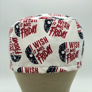 K&ouml;nnte beinhalten: Wei&szlig;e Stoff-Scrub-M&uuml;tze mit einem sich wiederholenden Muster aus schwarzen und wei&szlig;en Hockeymasken und dem Text "I Wish It Was Friday" in Rot.