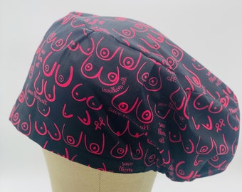 Puede incluir: Un gorro de quirófano negro con un diseño rosa de concienciación sobre el cáncer de mama. El gorro está cubierto de contornos rosas de senos con el texto "Save them all" repetido en todo el gorro.
