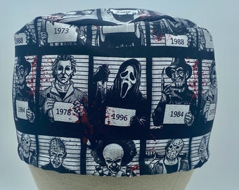 May include: Black and white fabric featuring a pattern of horror movie characters in mugshots. Each mugshot has a year printed below it, such as 1978, 1984, and 1996. The fabric has red splatters on it.