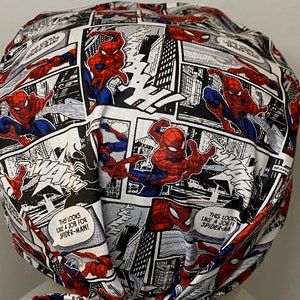 Pu&ograve; includere: Un berretto chirurgico in tessuto bianco, rosso e blu con un motivo a fumetti con Spider-Man. Il berretto ha un laccio sul retro. Il testo sul berretto recita "This looks like a job for Spider-Man!"