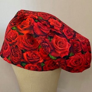 May include: A red and green scrub hat with a floral pattern of red roses.