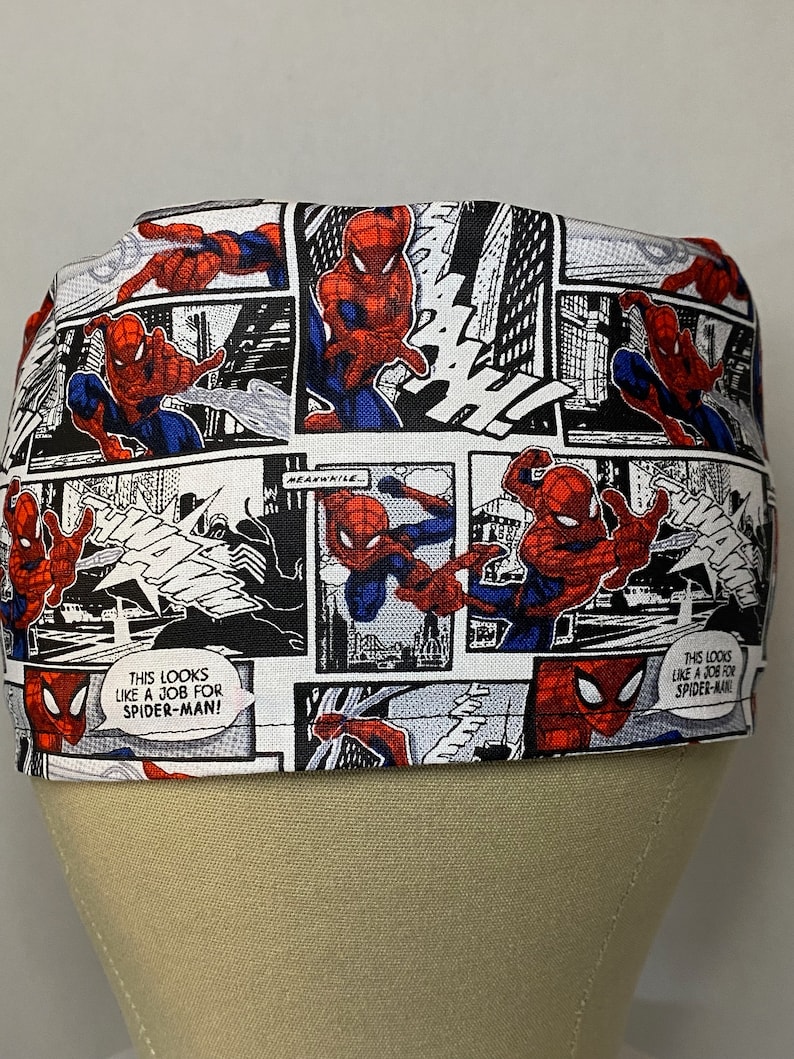 Pu&ograve; includere: Un berretto da lavoro in tessuto bianco con una stampa a fumetti con Spiderman in rosso e blu. La stampa include il testo "This looks like a job for Spiderman!"