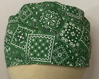 Può includere: Bandana verde con un motivo paisley bianco. La bandana è piegata e mostrata su una testa di manichino.