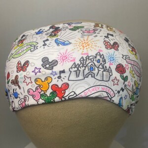 May include: White headband with a colourful doodle pattern featuring Mickey Mouse, Minnie Mouse, Cinderella's glass slipper, fireworks, and the text "Walt Disney World".
