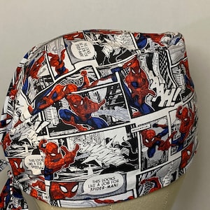 Pu&ograve; includere: Un berretto chirurgico bianco, rosso e blu con un motivo a fumetti con Spider-Man. Il testo sul berretto recita "This looks like a job for Spider-Man!"