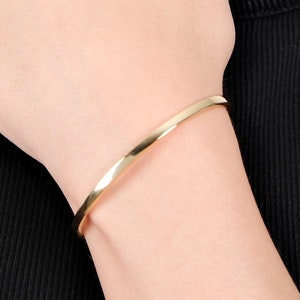 Puede incluir: Un brazalete de oro en la muñeca de una persona.