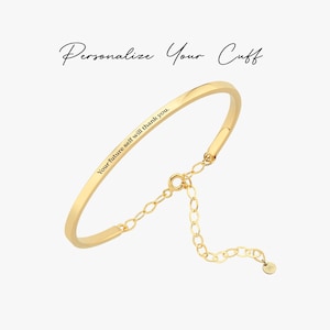 May include: A gold-colored cuff bracelet with the engraved text "Your future self will thank you." The bracelet has a delicate chain extension and a small charm. The text "Personalize Your Cuff" is above the bracelet.