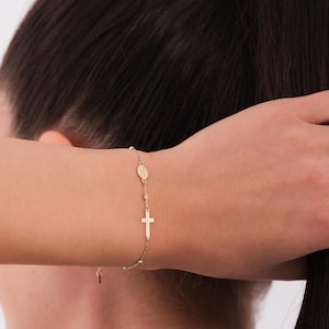 The 14K solid gold rosary bracelet for women shown on the wrist while styling hair.
