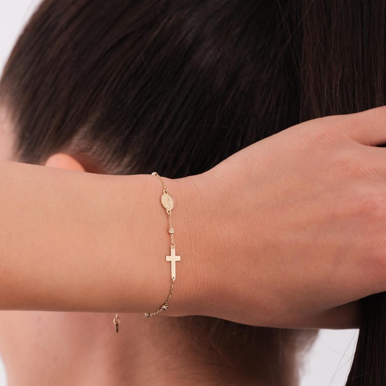 The 14K solid gold rosary bracelet for women shown on the wrist while styling hair.