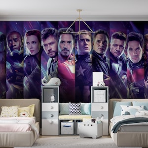 以下が含まれることがあります： アベンジャーズのキャラクターが描かれた大きな壁画のある子供部屋。ベージュのフレームのシングルベッド2台、白とグレーの収納ユニット、装飾用の枕があります。配色は紫、青、ベージュです。