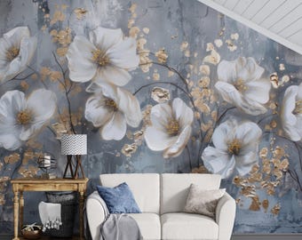 May include: A large floral wall mural featuring oversized white flowers with gold accents against a textured gray and blue background. A small wooden table, a lamp, and a white sofa are in front of the mural.