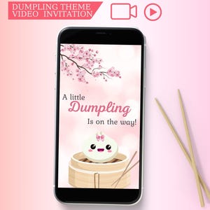 May include: A pink and white smartphone screen with a cartoon dumpling in a bamboo steamer. The text on the screen reads "A little Dumpling Is on the way!" with a pink cherry blossom branch in the background.
