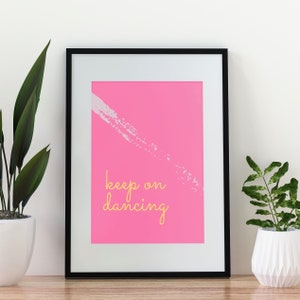 Puede incluir: Un póster rosa enmarcado con una pincelada blanca y el texto "keep on dancing" en amarillo.