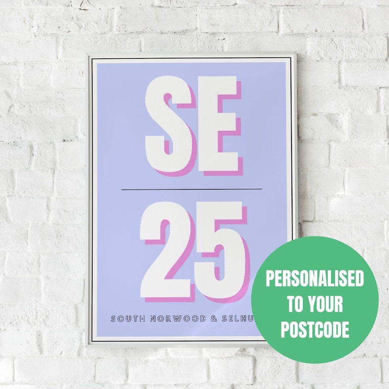 May include: A light blue poster with white and pink text. The text reads "SE 25" and "SOUTH NORWOOD & SELHURST". The poster is framed in a white frame and is hanging on a white brick wall. A green circle with white text reads "PERSONALISED TO YOUR POSTCODE".