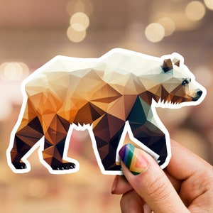 May include: A geometric brown bear sticker with a white outline. The bear is walking to the right and has a low-poly style.