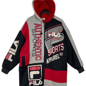 Puede incluir: Chaqueta con capucha Fila con bloques de color en negro, rojo y gris. La chaqueta presenta el logotipo de Fila y las palabras "AUTHENTIC SPORTS APPAREL" en blanco y rosa. Tiene un forro interior rojo y una cremallera completa.