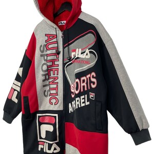 Puede incluir: Una sudadera con capucha con cremallera Fila en rojo, negro y gris. La chaqueta presenta el logotipo de Fila y las palabras "Authentic Sports Apparel". La capucha es roja con un forro suave. Tiene cremallera frontal y dos bolsillos.