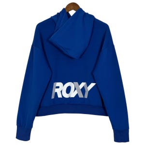May include: A royal blue hoodie with a hood and long sleeves, hanging on a wooden hanger. The word "ROXY" is printed in white across the back of the hoodie.