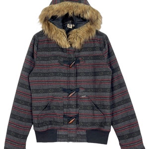 May include: A grey and red striped hooded jacket with a faux fur lined hood and toggle closures. The jacket has a black ribbed knit waistband and cuffs.