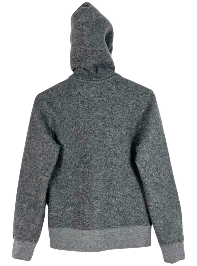 Puede incluir: Una sudadera con capucha gris con capucha con cord&oacute;n y pu&ntilde;os y dobladillo de canal&eacute;. La vista trasera de la sudadera muestra la capucha y la parte superior de la espalda de la prenda. La tela parece ser un material suave similar al forro polar.
