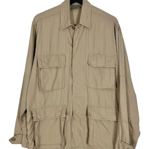 Könnte beinhalten: Eine beige Utility-Jacke mit mehreren Taschen und einem Knopfleistenverschluss.