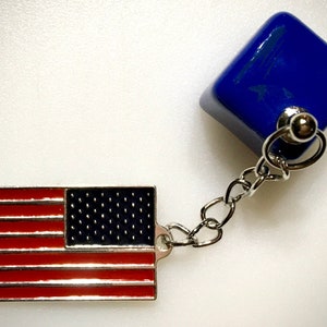 May include: A silver keychain with a blue cube charm and a red, white, and blue American flag charm.