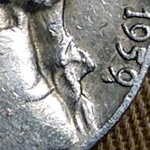 May include: Close-up of a silver coin with the year 1959 visible. The coin features a profile of a person, with details of the face and hair. The coin's edge and surface show signs of wear.