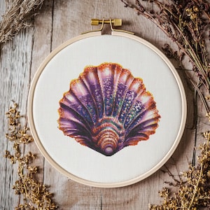May include: A close-up of a colorful, iridescent seashell with a purple, pink, and orange color scheme. The shell is displayed in a wooden embroidery hoop.