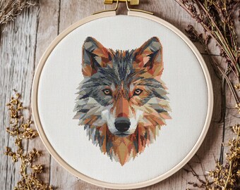 Peut inclure: Un motif de point de croix représentant la tête d'un loup avec un design géométrique. La fourrure du loup est un mélange de brun, de gris et de blanc.