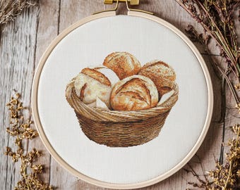 Könnte beinhalten: Ein brauner Weidenkorb gefüllt mit fünf runden, goldbraunen Brötchen. Der Korb steht auf einer hellbraunen Holzoberfläche.