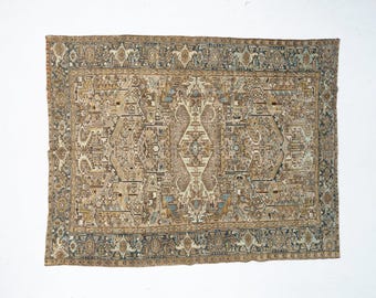 May include: A rectangular area rug featuring a complex, symmetrical pattern in shades of beige, tan, slate blue, and cream. The design includes a central medallion surrounded by intricate geometric and floral motifs, enclosed by a wide, detailed border.