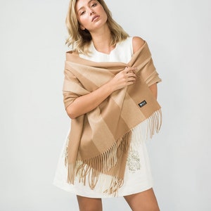 May include: A brown and beige striped scarf with fringe. The scarf is made of soft, warm material and is perfect for keeping you warm in the winter.
