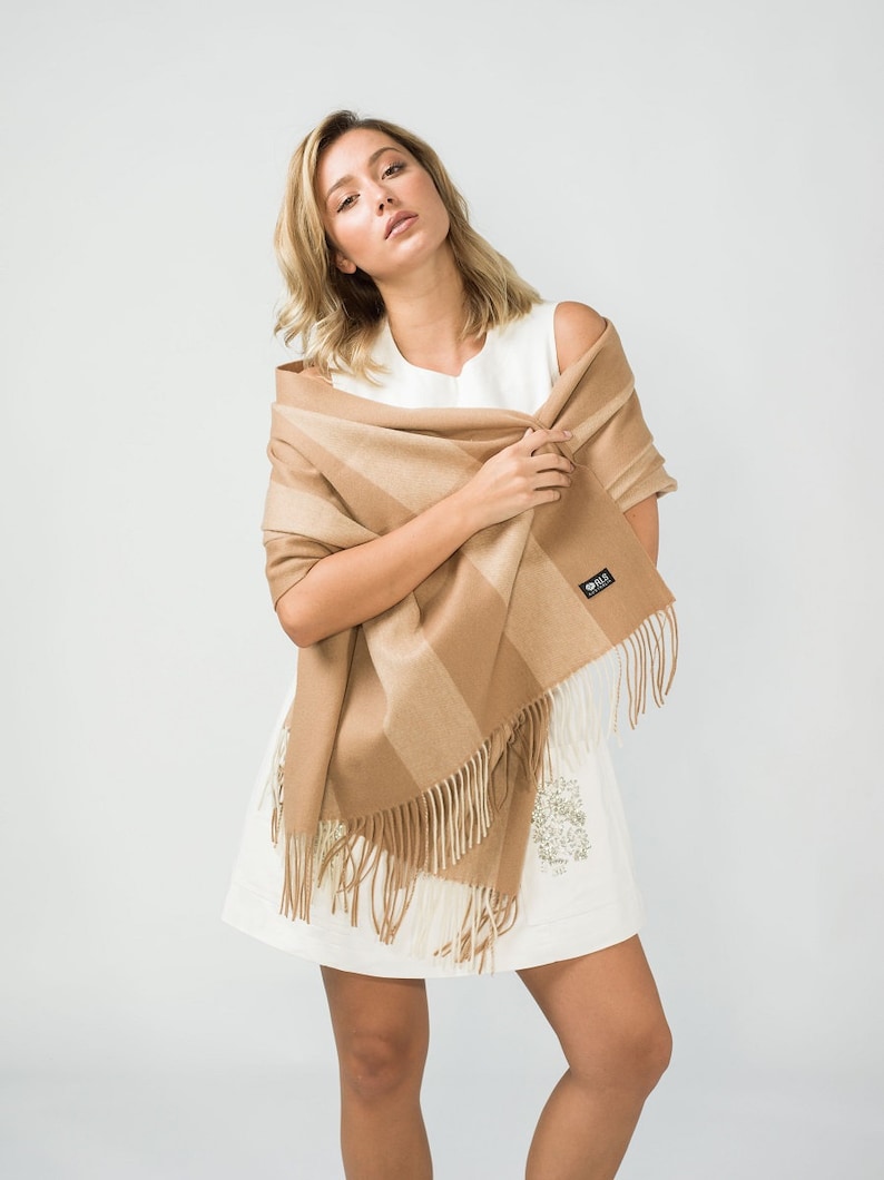 May include: A brown and beige striped scarf with fringe. The scarf is made of soft, warm material and is perfect for keeping you warm in the winter.