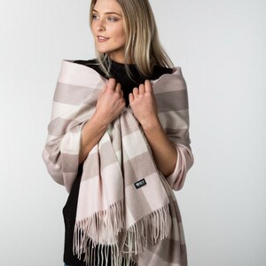 May include: A pink and white striped scarf with fringe. The scarf has a small black tag with the text "BLS" on it.