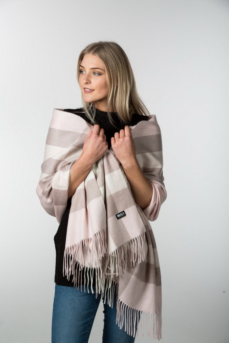 May include: A pink and white striped scarf with fringe. The scarf has a small black tag with the text "BLS" on it.
