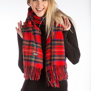 May include: A red and black plaid scarf with fringe. The scarf is worn by a person with long blonde hair. The scarf has a small logo that says "ALS Australia".