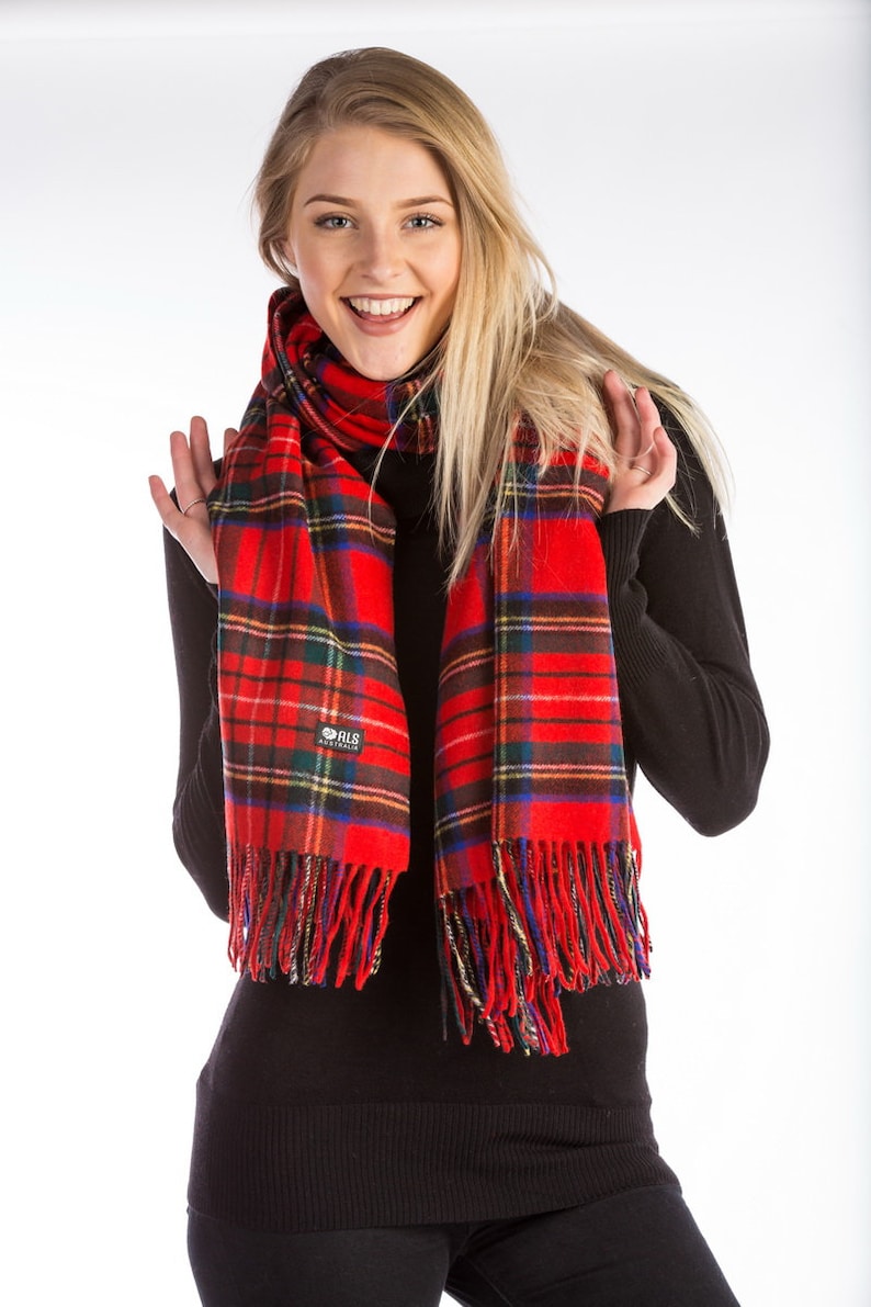 May include: A red and black plaid scarf with fringe. The scarf is worn by a person with long blonde hair. The scarf has a small logo that says "ALS Australia".