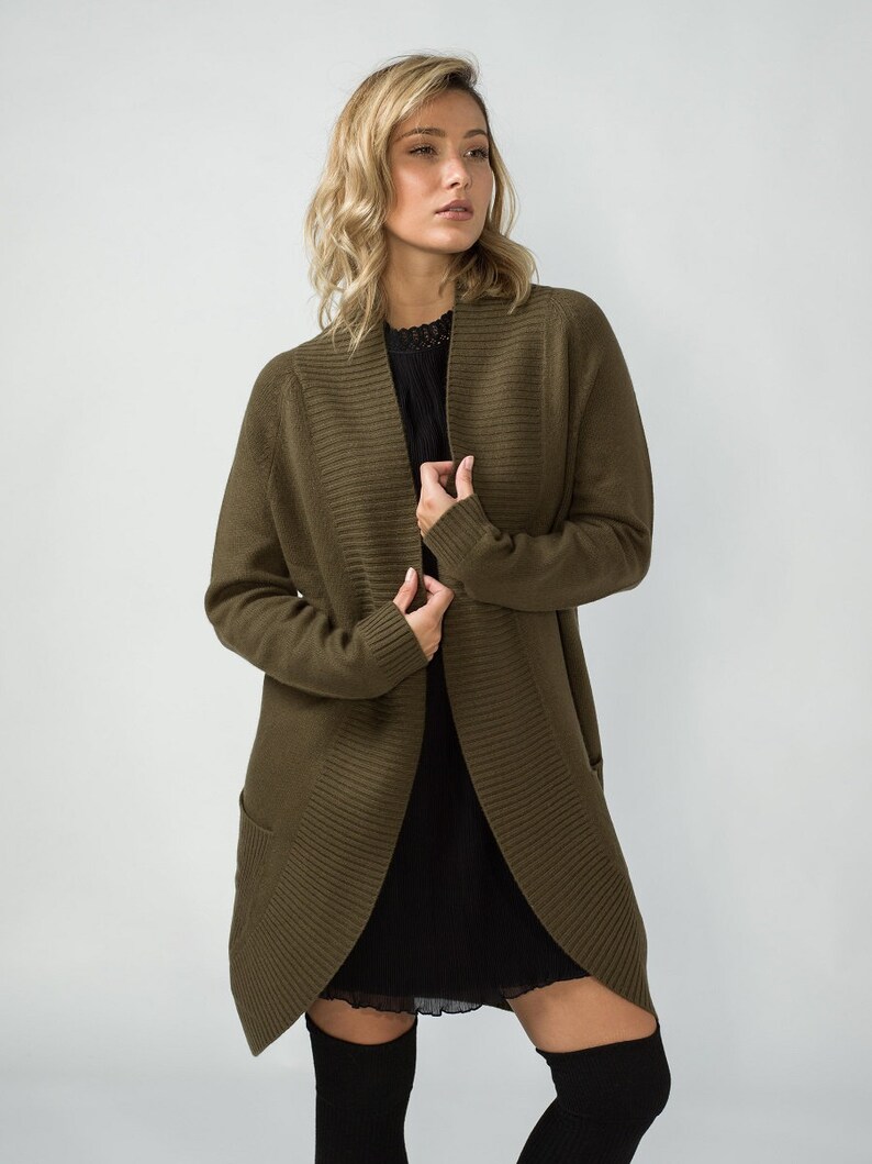 K&ouml;nnte beinhalten: Ein langer, olivgr&uuml;ner Cardigan mit Schalkragen und Taschen. Der Cardigan ist aus weichem, gestricktem Stoff.